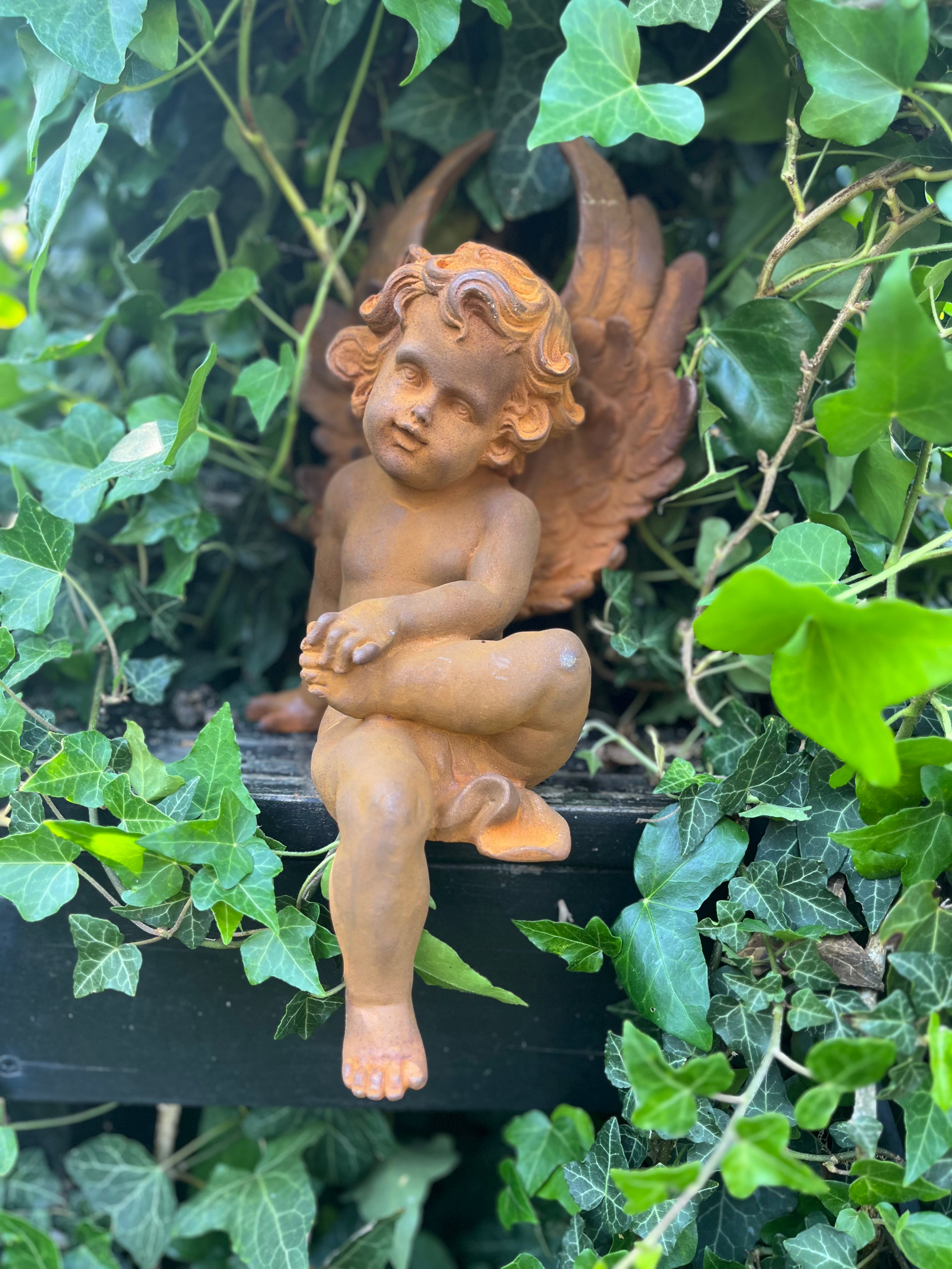 Zittende engel van gietijzer met voet op bovenbeentje - Brocante bij Ingie