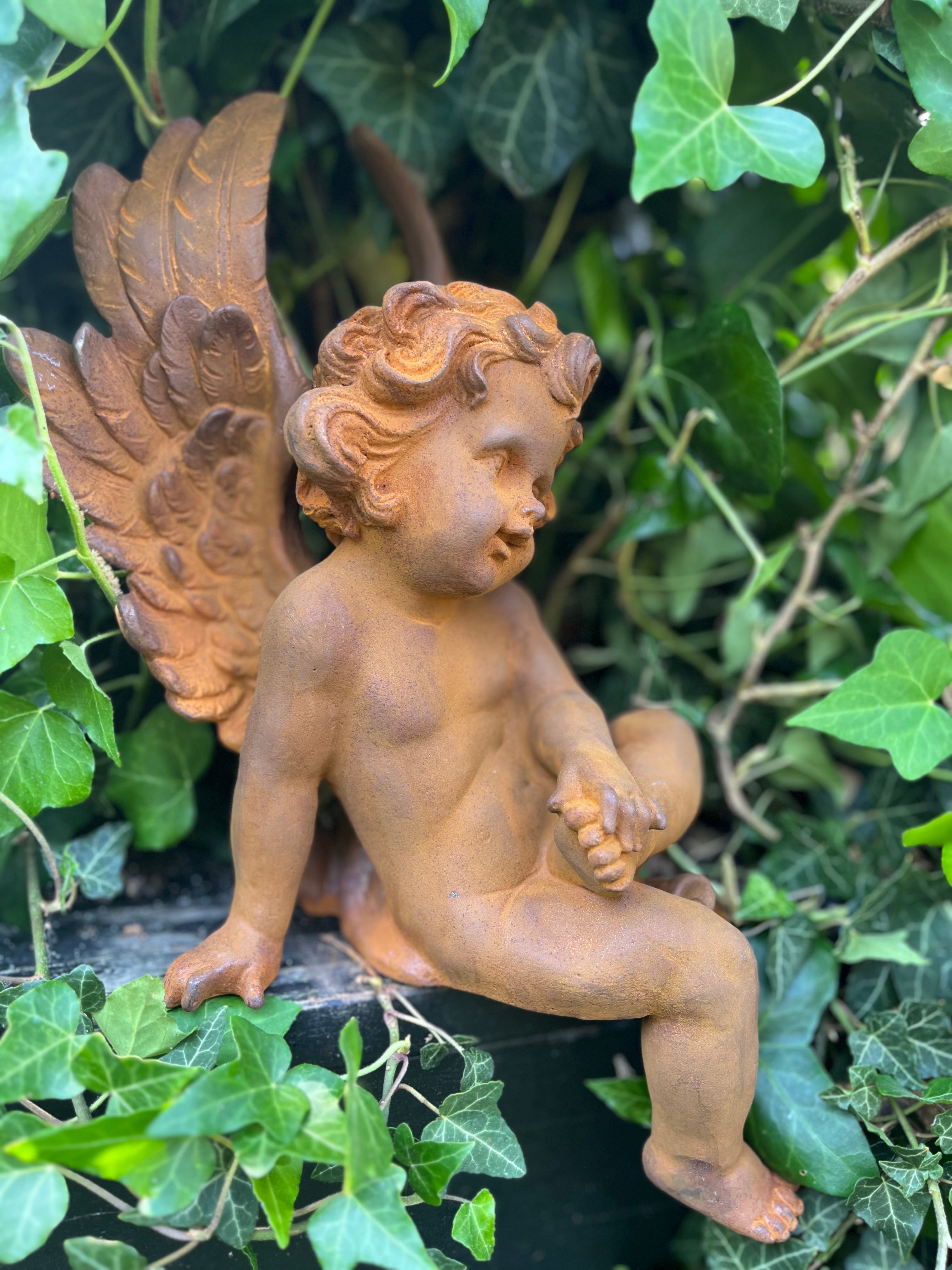 Zittende engel van gietijzer met voet op bovenbeentje - Brocante bij Ingie